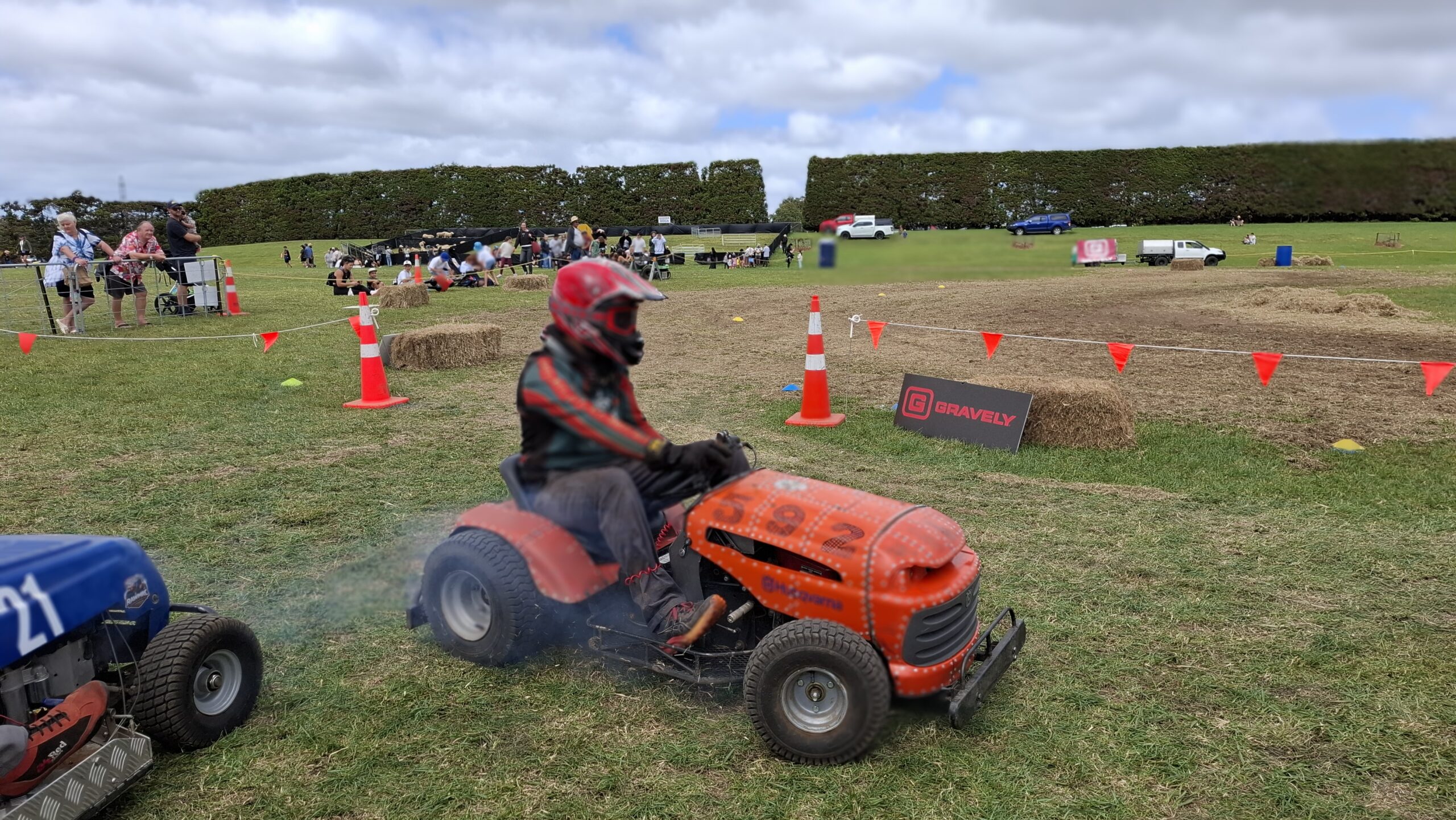 Driver racing a ride-on lawn mower around the track