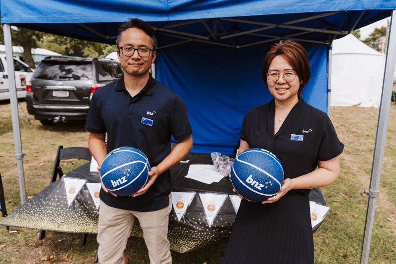 Two BNZ staff holding blue basketballs at their stand