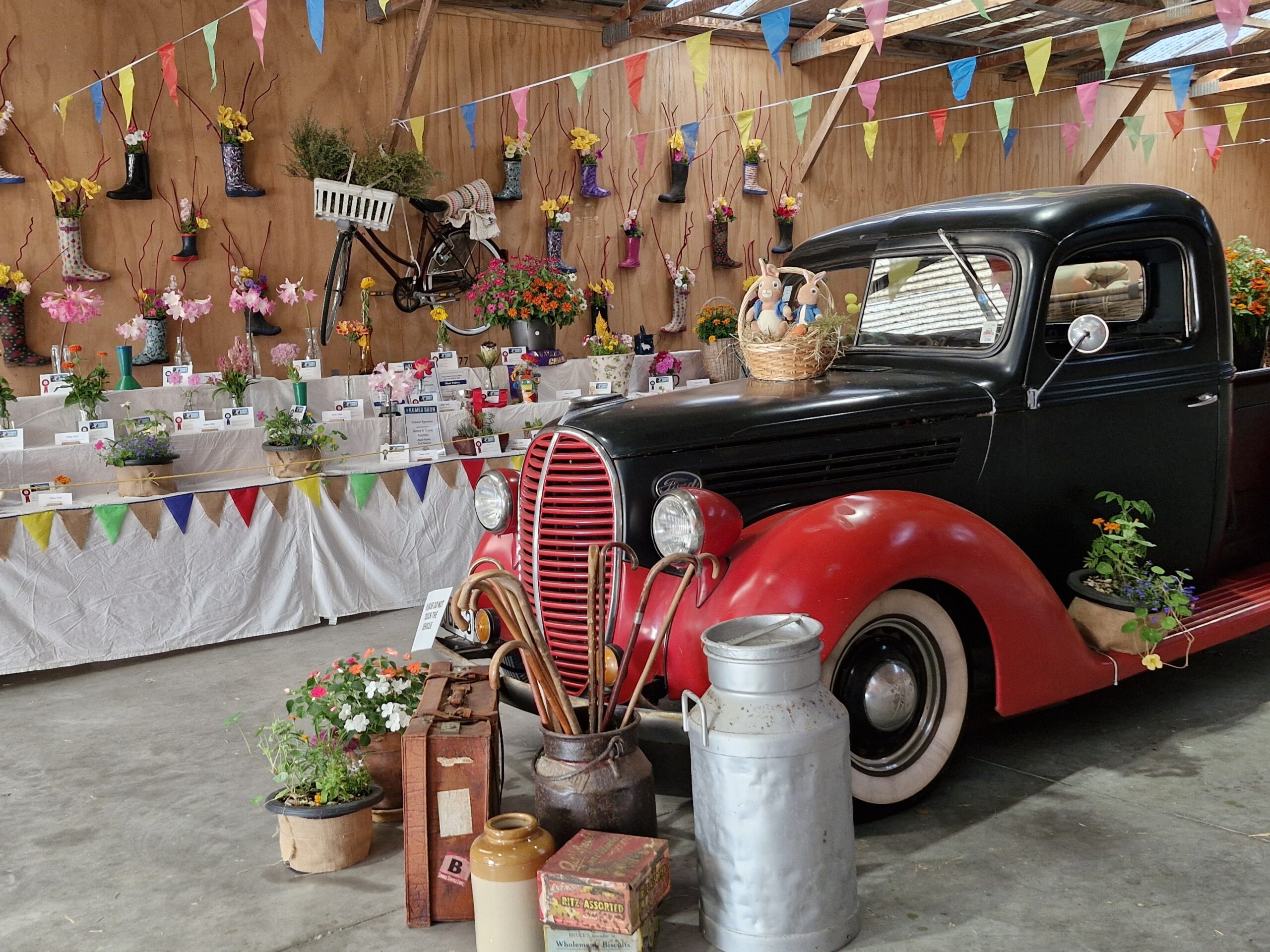 Indoor display with bunting, flowers, milk cans and a vintage red truck