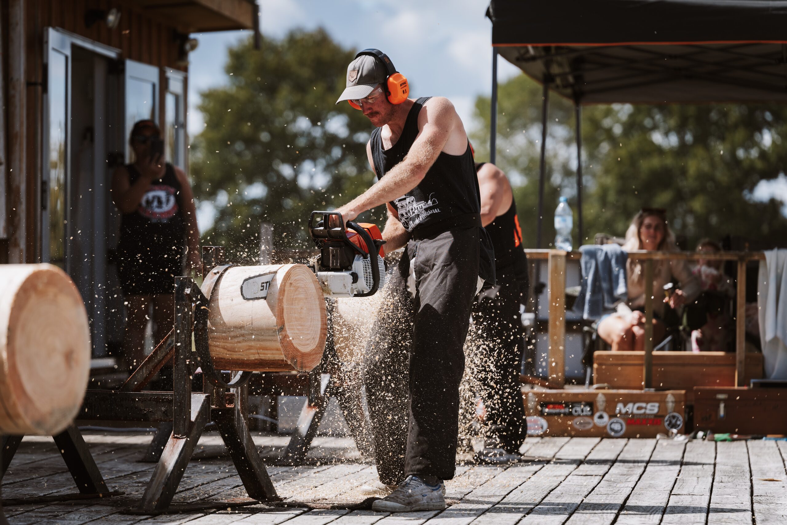 Woodchopper sawing through a log with a chainsaw, sawdust flying