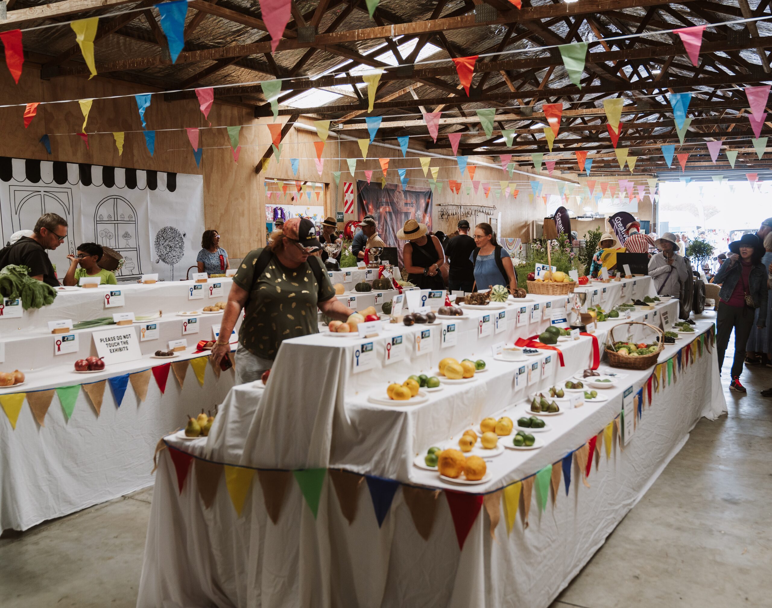 Indoor exhibition hall with bunting and tables of baking and produce entries
